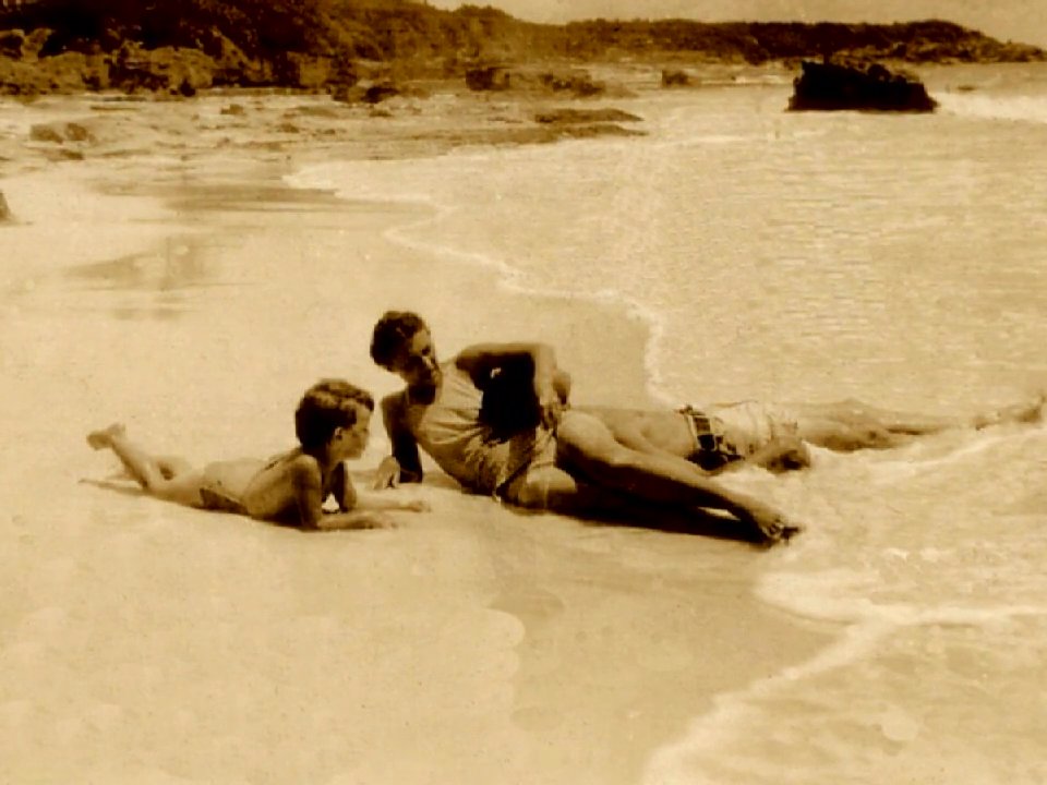 A family enjoys a seaside holiday, transitioning from posed outdoor portraits to candid moments of a child playing in the sand and adults socializing on the beach.