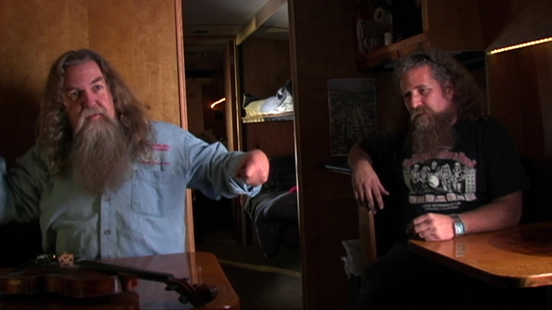 A long-bearded musician shares insights during an intimate interview before transitioning to a focused harmonica performance in a studio setting.