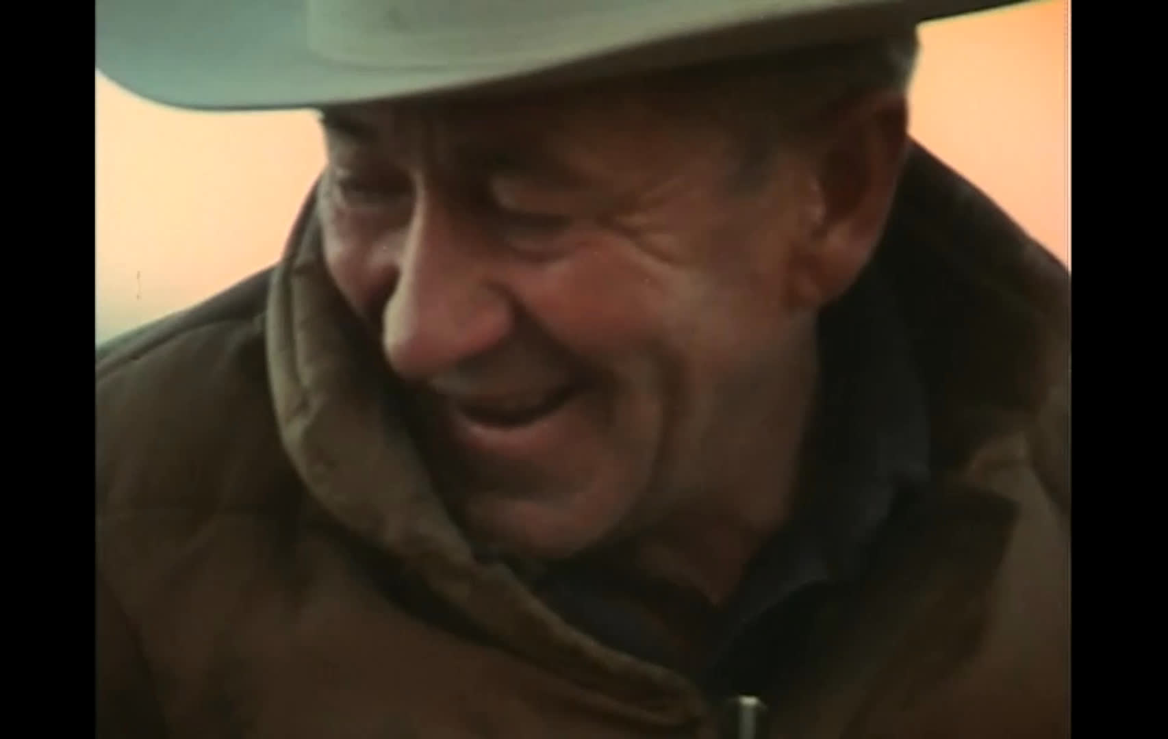Ranch hands prepare their horses and gather with coiled ropes before riding across open, rugged range. Cowboys on horseback work together to move cattle, while a ranch hand smiles during the preparations.