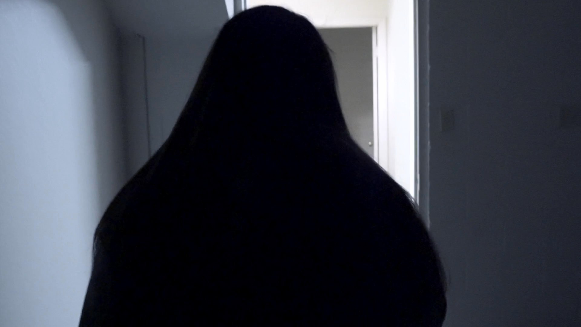 A man lies incapacitated in a hospital bed while a woman receives somber news during a phone call in a kitchen.