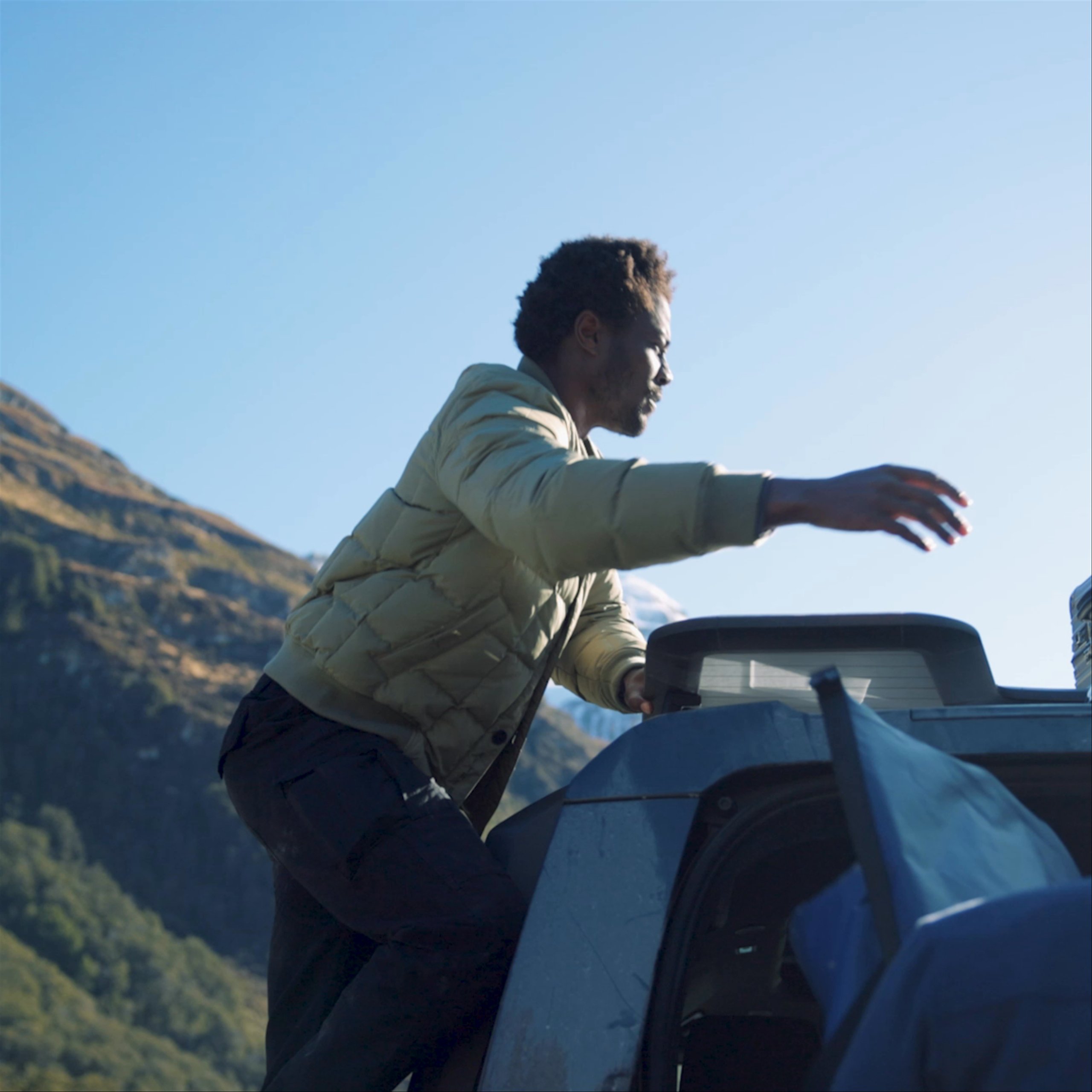 Video of man pulling luggage from the top of a Defender vehicle in New Zealand landscape