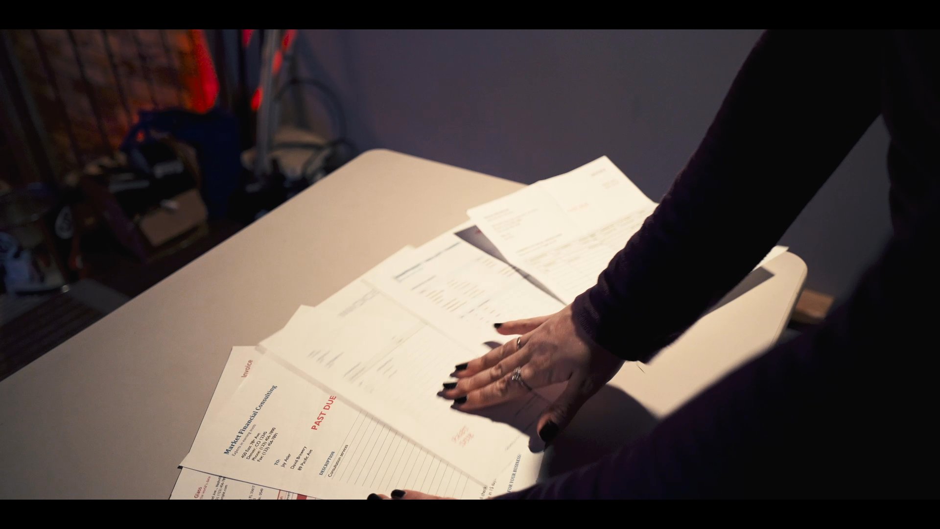A woman organizes and reviews a series of documents at a desk within an office environment. She systematically sorts the papers, ensuring they are prepared for further administrative processing.