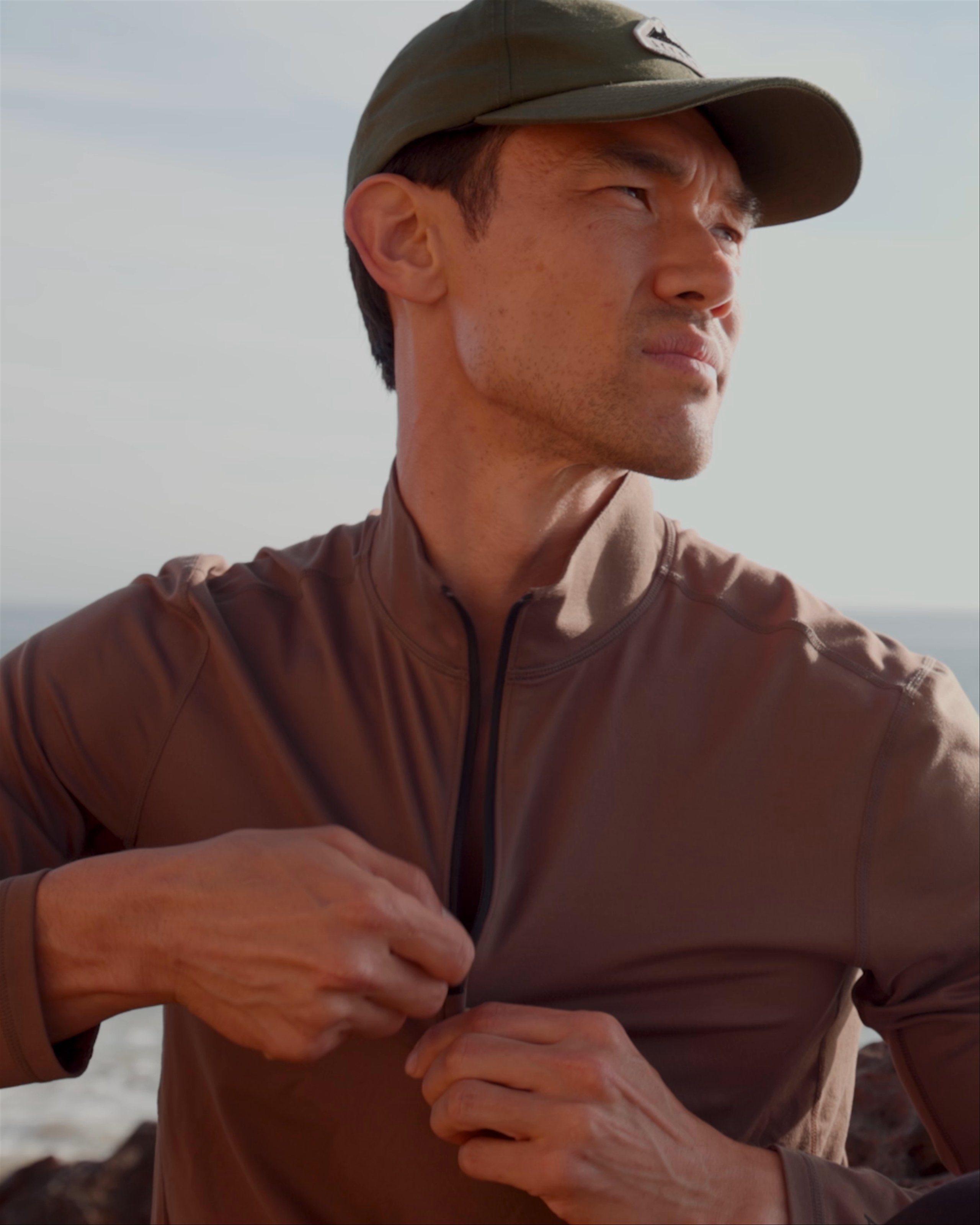 Man in Trek Articulated Half-Zip zipping up shirt with ocean in background