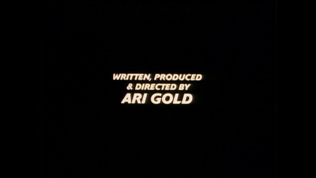 Production credits display over a night view of a sprawling city landscape, followed by a brief cut to a close-up of a dollar bill design.