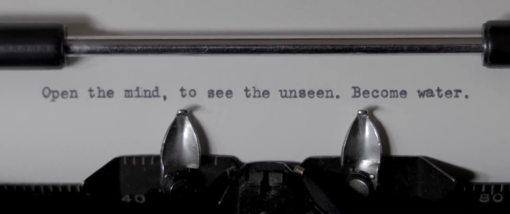A surfer waits in the calm ocean during sunset, transitioning to a close-up of a typewriter printing a meditative phrase. The sequence concludes with a man resting in bed, juxtaposed with abstract silhouettes that evoke deep introspection.