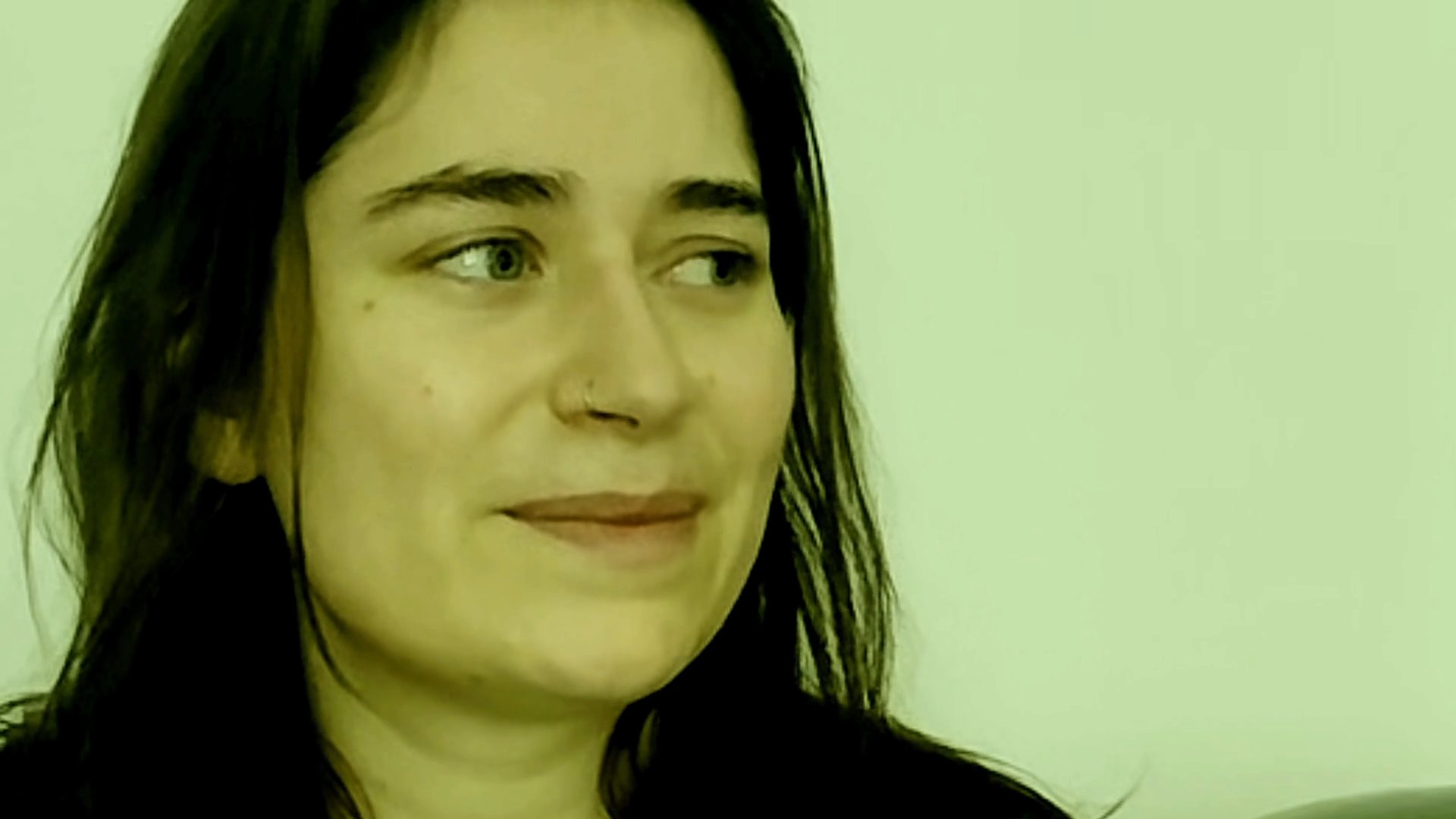 A woman speaks directly to the camera, sharing thoughts and expressions in an interview-style setting.