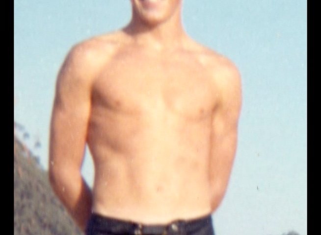 A surfer relaxes near a beachside rental shop before transitioning to the water to ride waves. The footage captures the transition from casual coastal downtime to active surfing in the ocean.