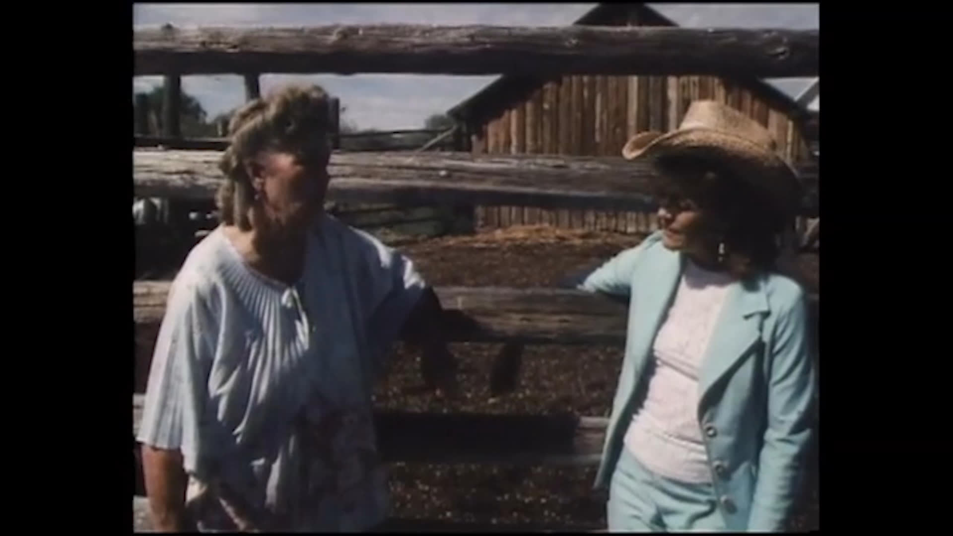 Two women speak beside a ranch corral as one reflects on a woman’s life and work around horses and cattle. A rider then guides a horse across dry open range among grazing cows.
