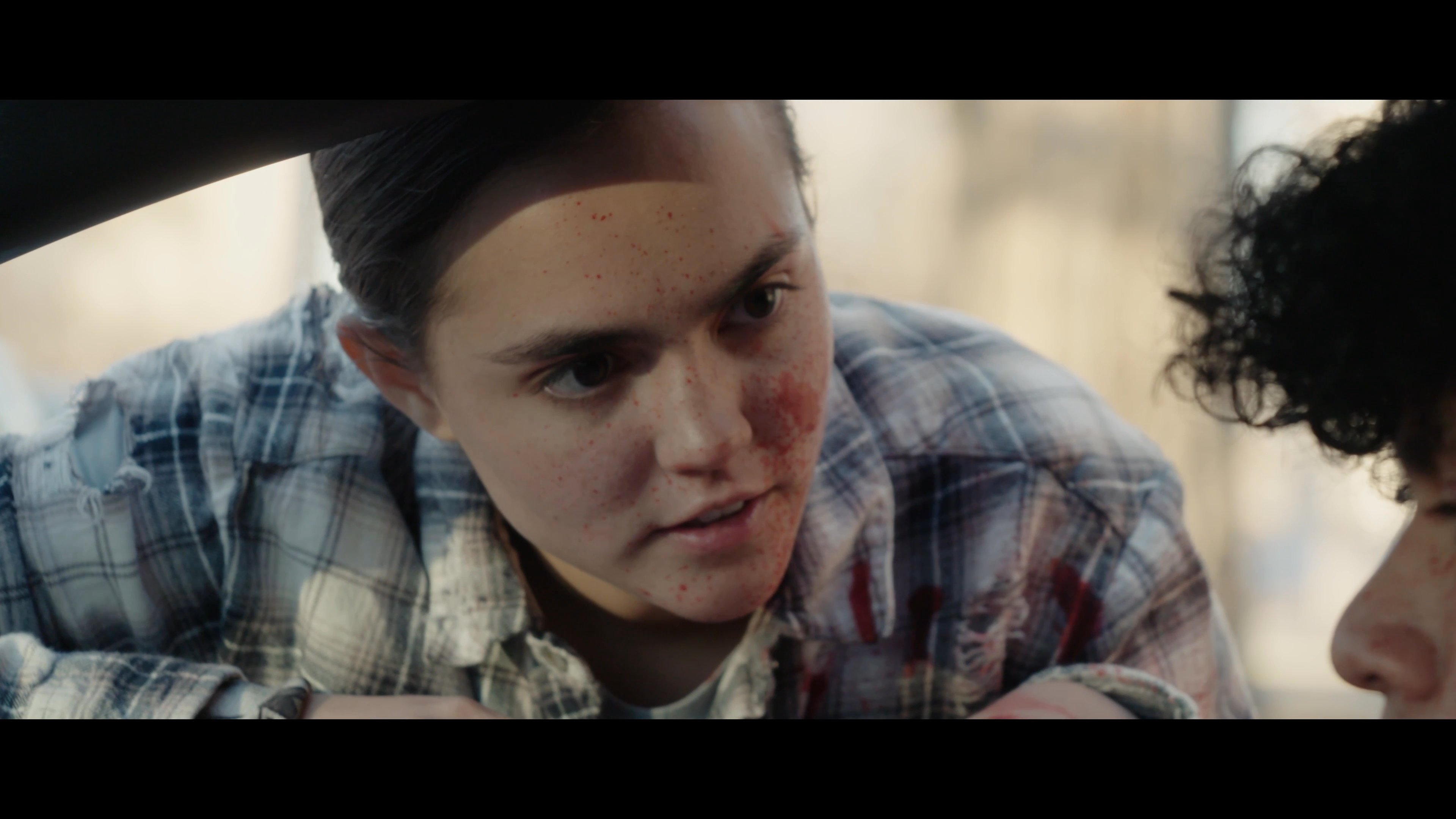 An injured young woman in a blood-stained shirt urgently confronts individuals inside a convertible car. Tense communication ensues between the parties during the roadside encounter.