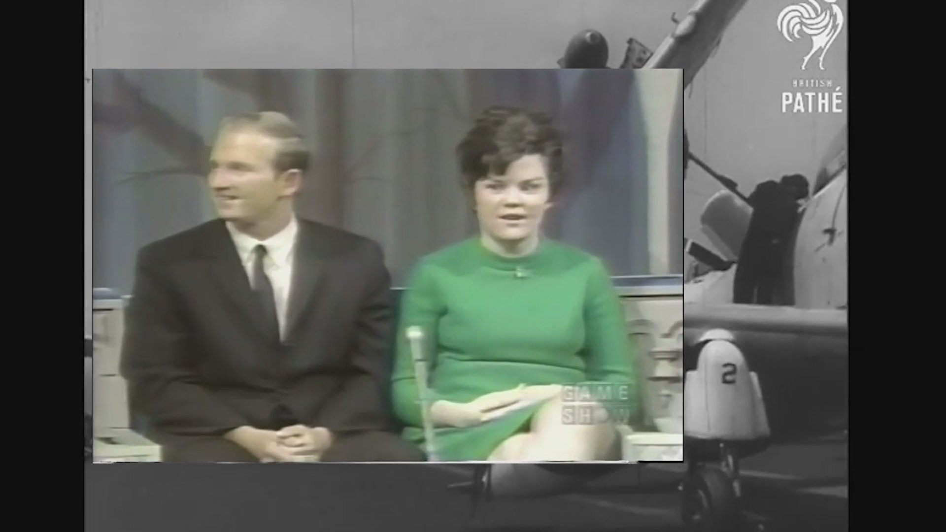 Participants compete on the vintage television game show The Newlywed Game, featuring studio interactions and historical broadcast commentary.