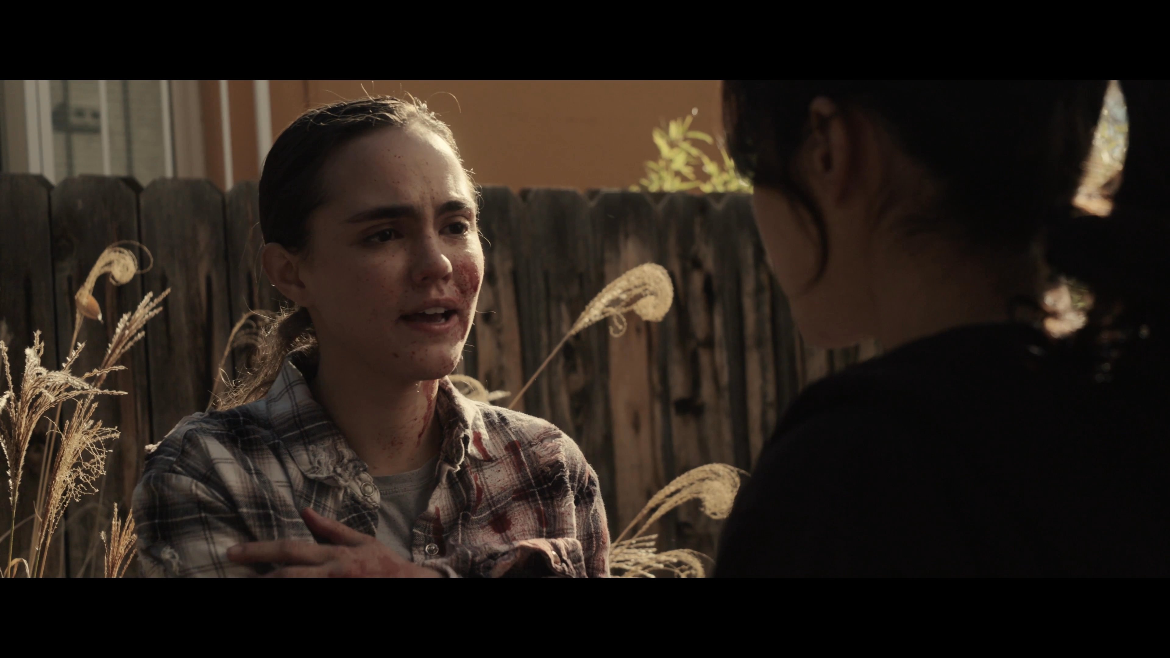 An emotionally distressed individual receives comfort from a friend in an outdoor setting, while another person processes personal turmoil in a home kitchen. The scene portrays themes of vulnerability, shared hardship, and interpersonal connection.