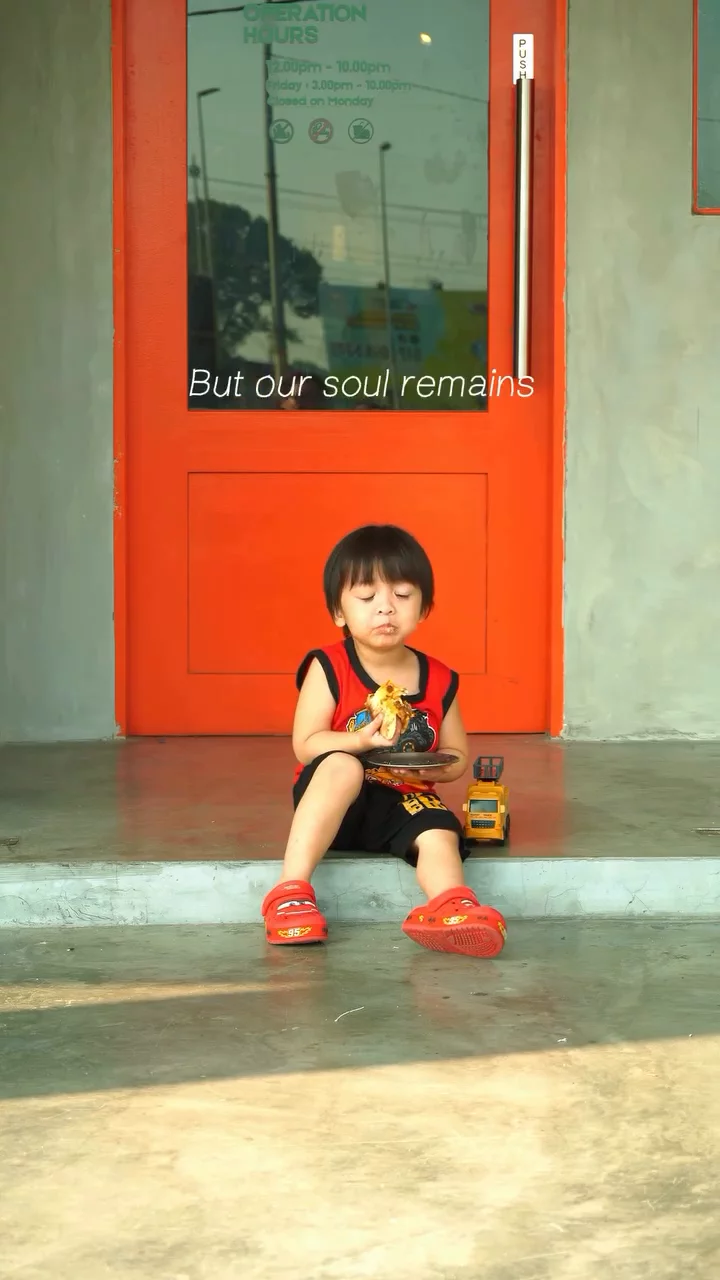 Child seated in front of a bright red doorway