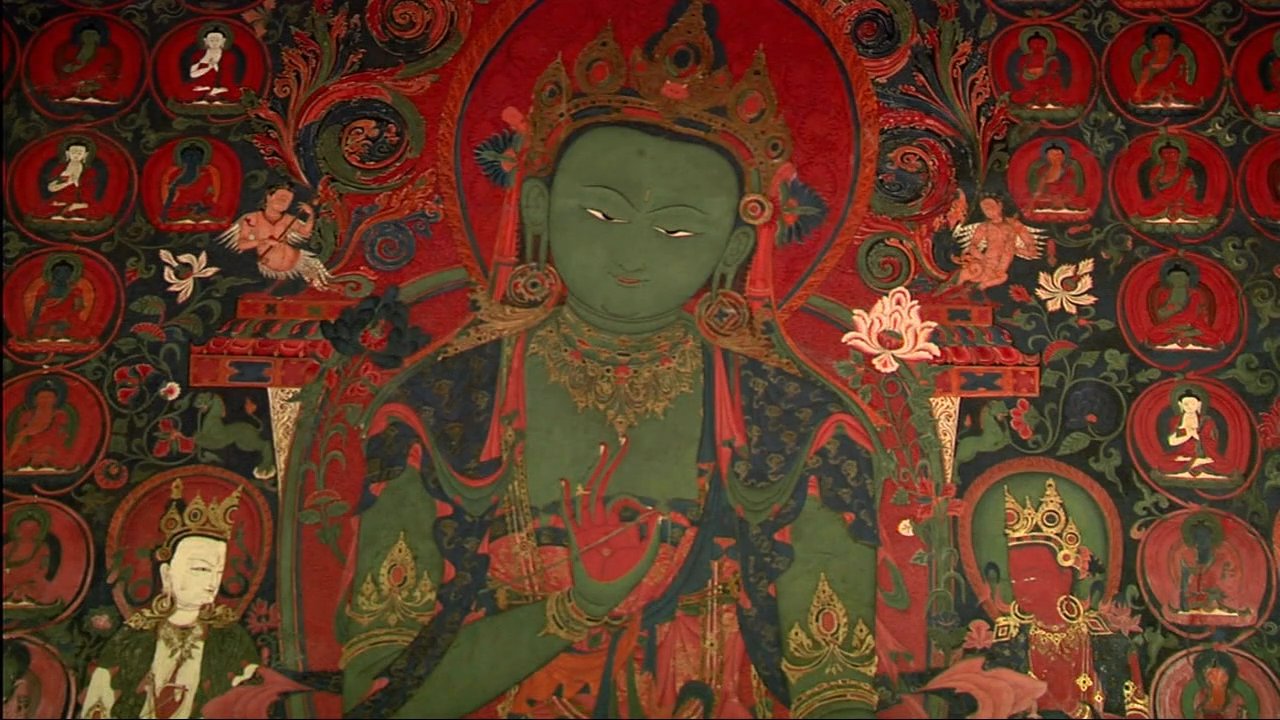 An expert discusses the historical significance of ornate thangka paintings while a photographer captures detailed images of the sacred artwork.