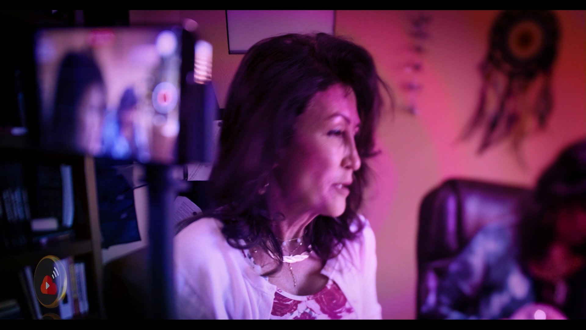 A woman participates in a mystical-themed video interview, appearing both on screen and reflected inside a crystal ball. The production features a stylized, colorful aesthetic typical of digital content creation.