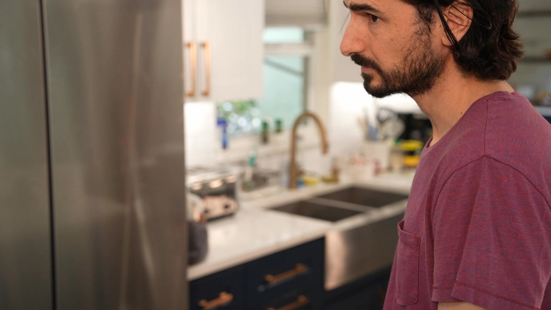 A group gathers in a kitchen to initiate a video call on a smartphone, connecting with relatives through mobile technology.