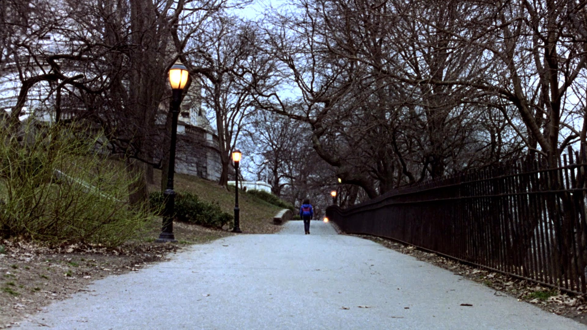 A man wearing a patterned beanie and scarf walks through a winter park before meeting with two acquaintances. The scene briefly transitions into a stylized animation sequence featuring a helicopter before returning to the group walking together.