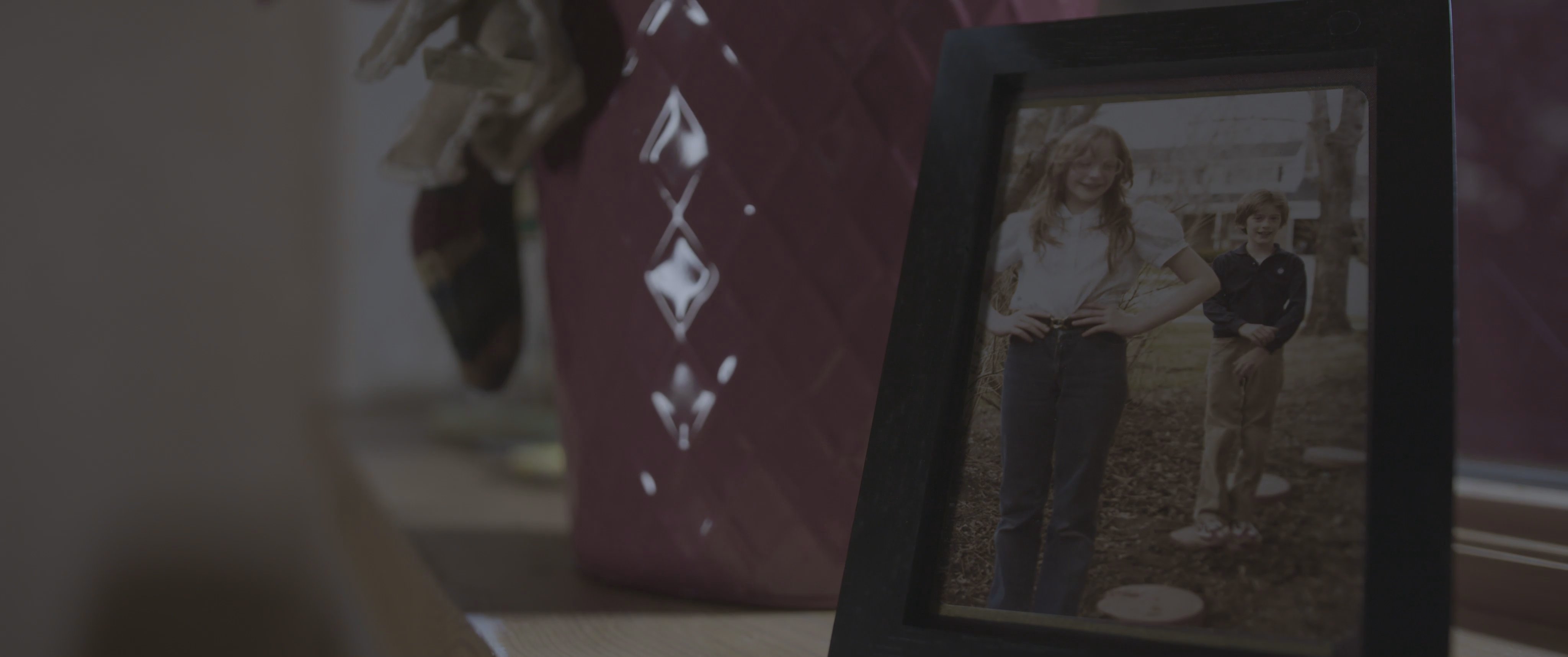 A somber sequence depicts a man engaged in a serious phone call while a woman rests nearby, transitioning to a framed family photograph before displaying film production credits.