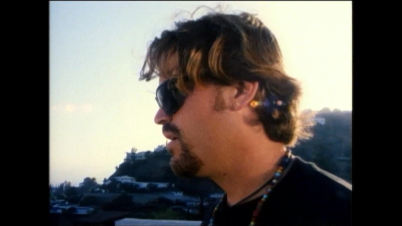 A man and woman engage in a tense conversation while overlooking an expansive city view at sunset. The sequence utilizes alternating close-ups to capture their animated expressions and emotional exchange.