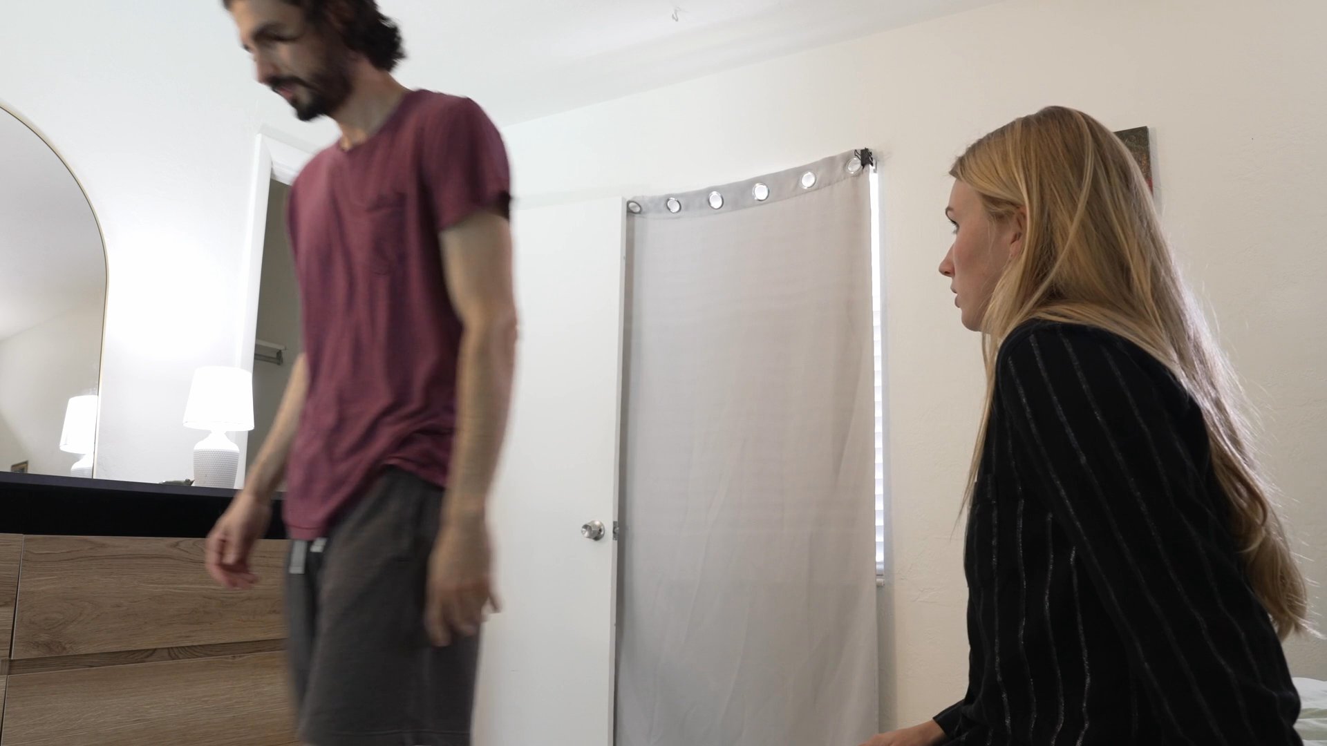 A woman engages in a serious, emotionally charged conversation with her partner in a bedroom setting. As the discussion concludes, the woman exhibits signs of distress and exhaustion.