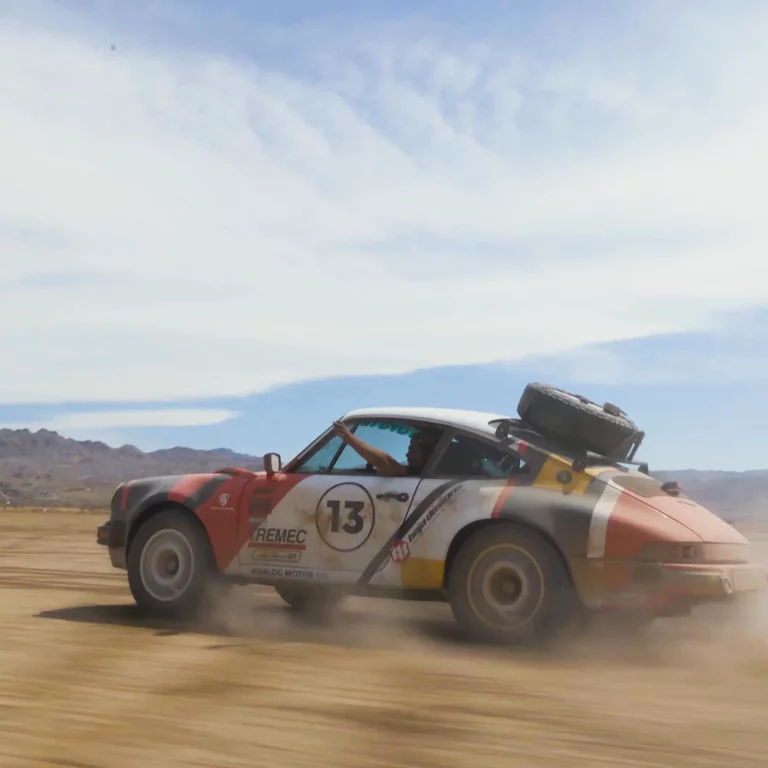 Vintage Porsche racing through desert landscape