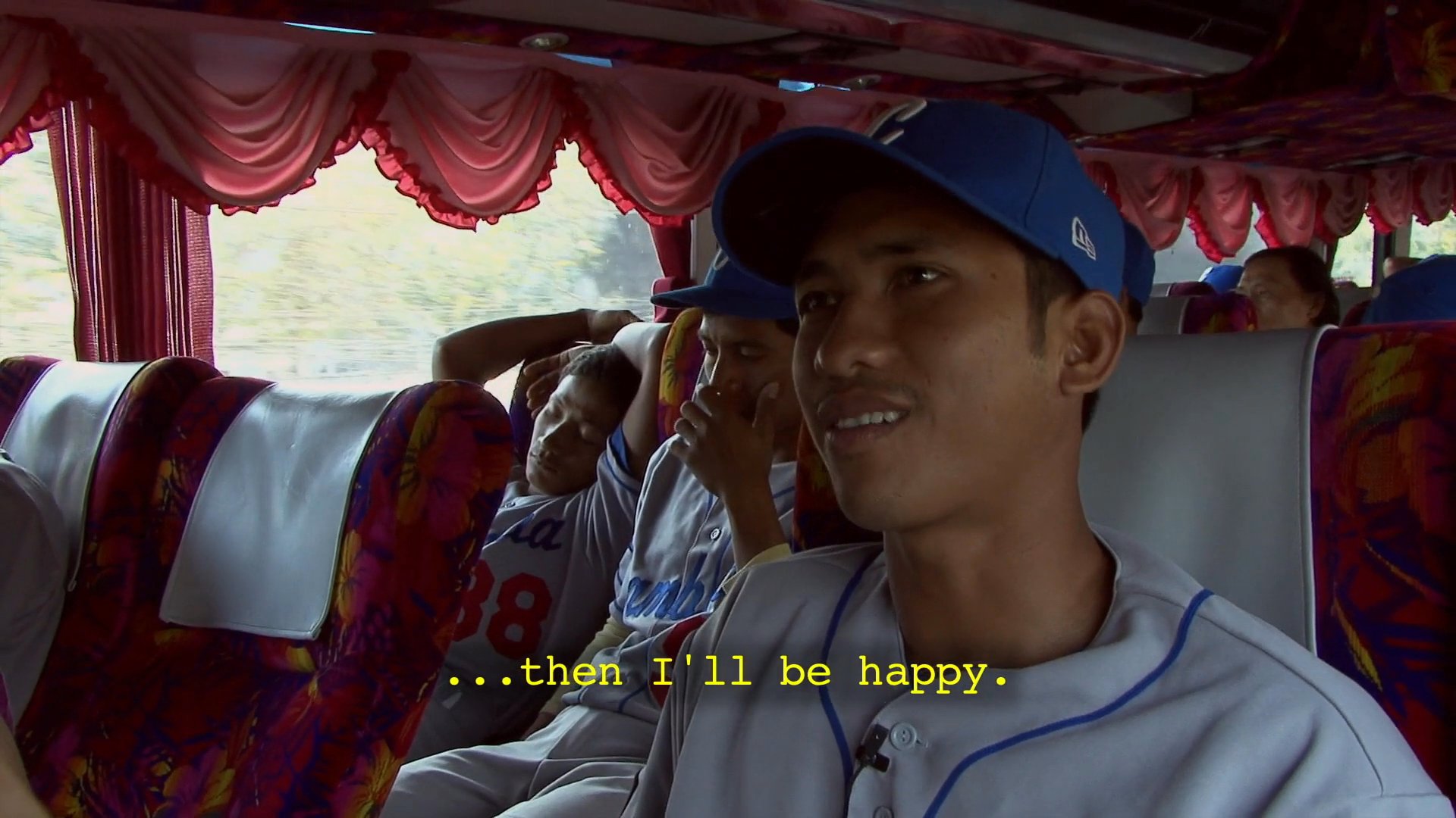 A baseball player discusses the importance of sportsmanship and competing with experienced teams while traveling on a bus with his teammates.