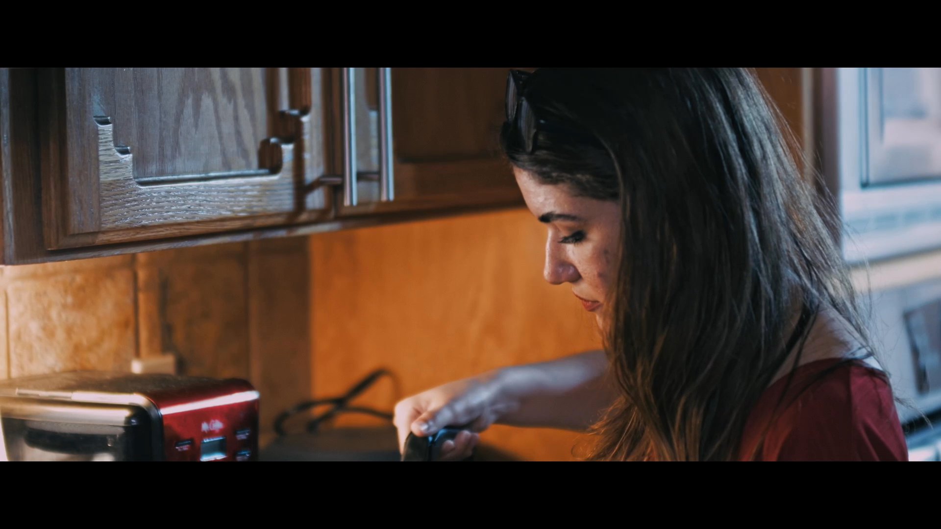 A compassionate caregiver tends to an elderly man, ensuring his comfort before preparing a warm beverage in the kitchen. The scene illustrates routine domestic care and the supportive relationship between a professional and their client.
