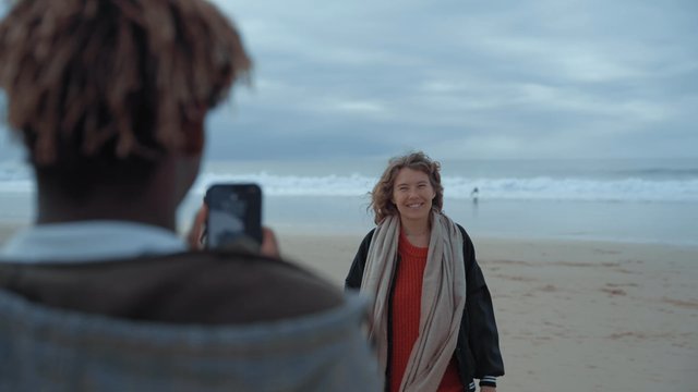 A guy photographs his female friend on the beach