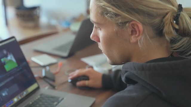 A blonde man works on a laptop in his home office