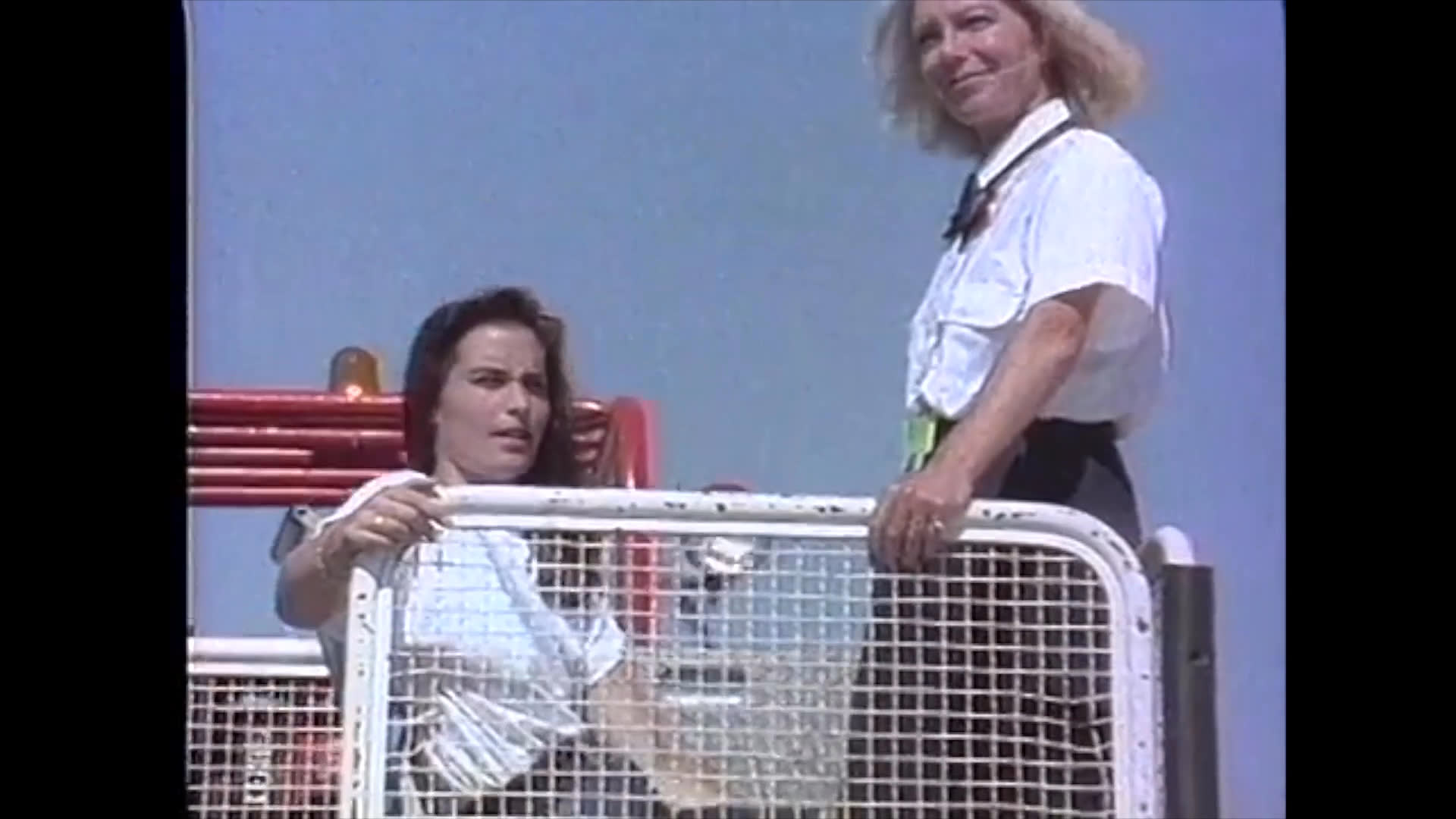 Ground crew assist a passenger in a wheelchair onto a high-reach lift platform to facilitate boarding an aircraft.