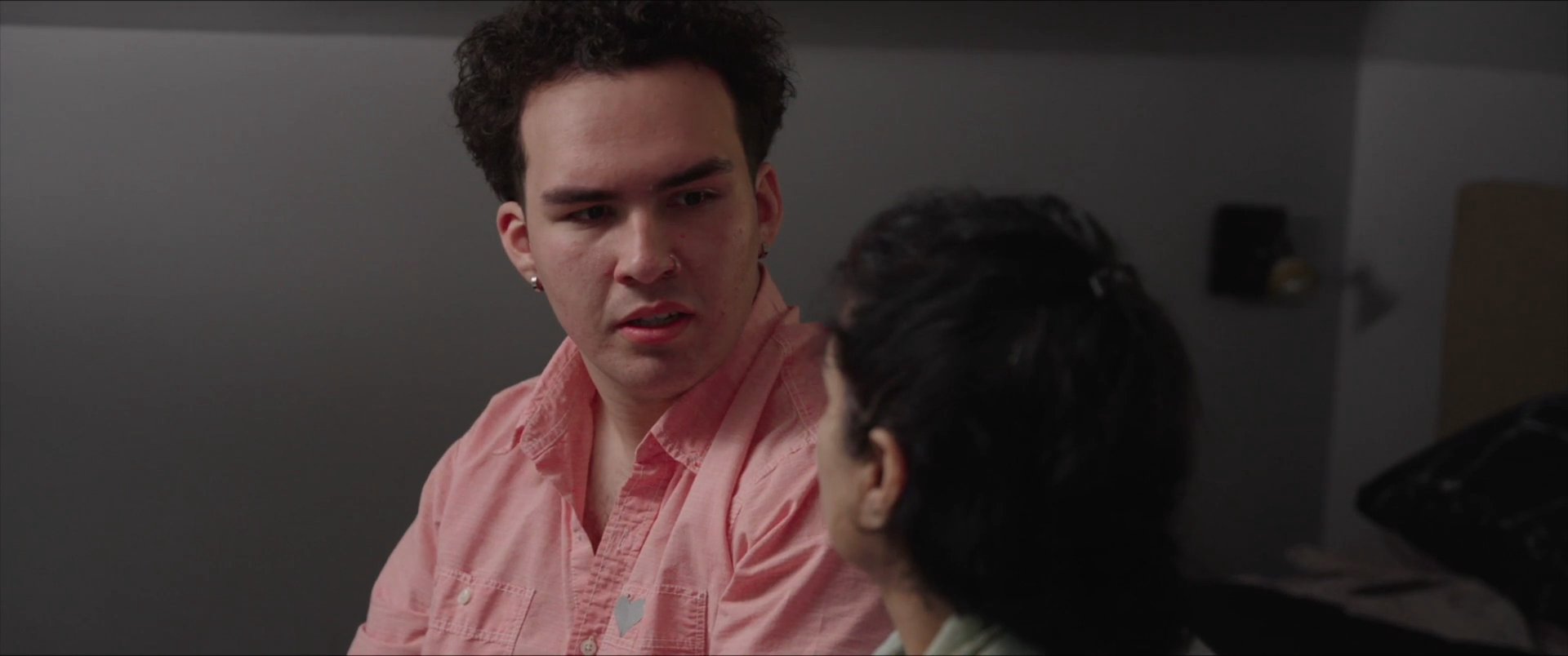 A woman and her son engage in a serious, focused conversation within a domestic bedroom setting.