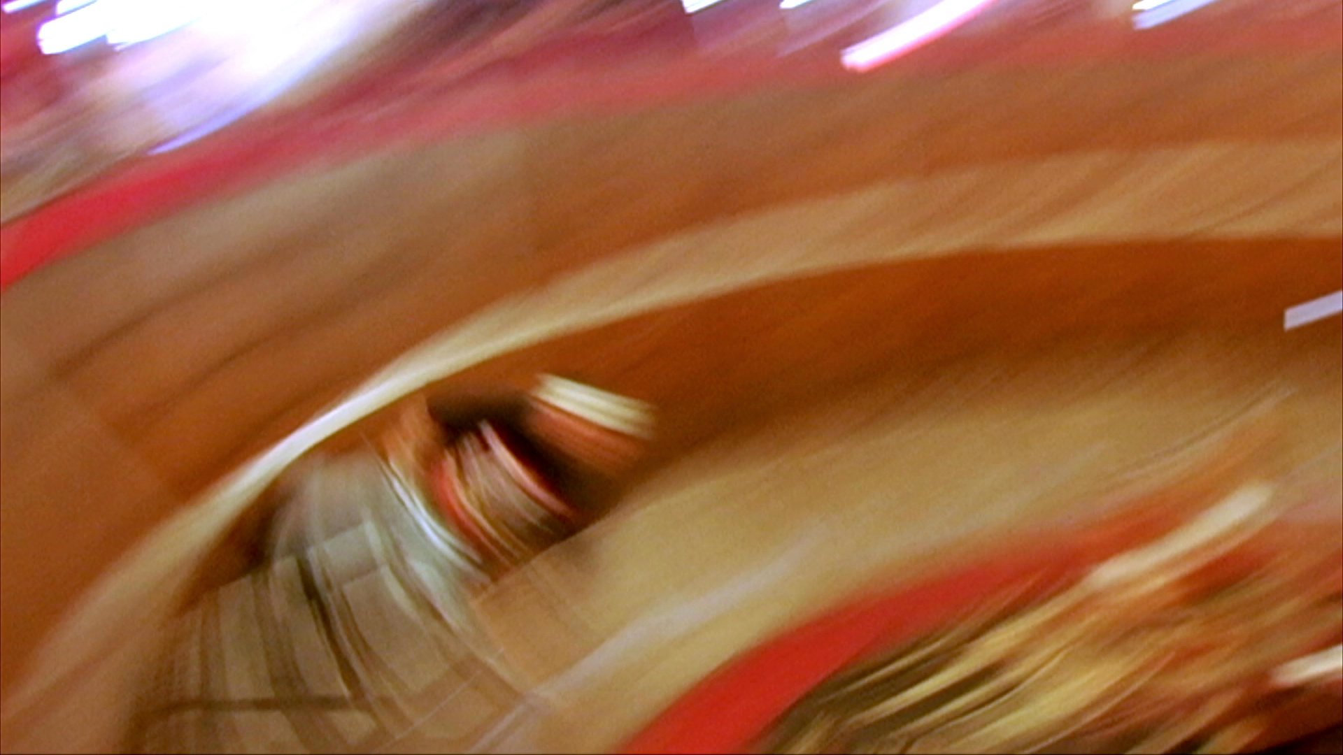 A motorcycle stunt performer rides a bike along the steep, vertical walls of a circular wooden arena before posing with his partner inside the structure.