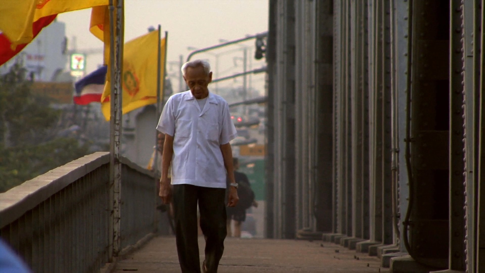 A man walks across a bridge over the Chao Phraya River, followed by street-level views of traditional tuk-tuk transport and bustling traffic in Bangkok.
