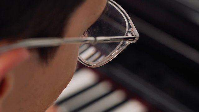 Man wearing glasses playing the piano