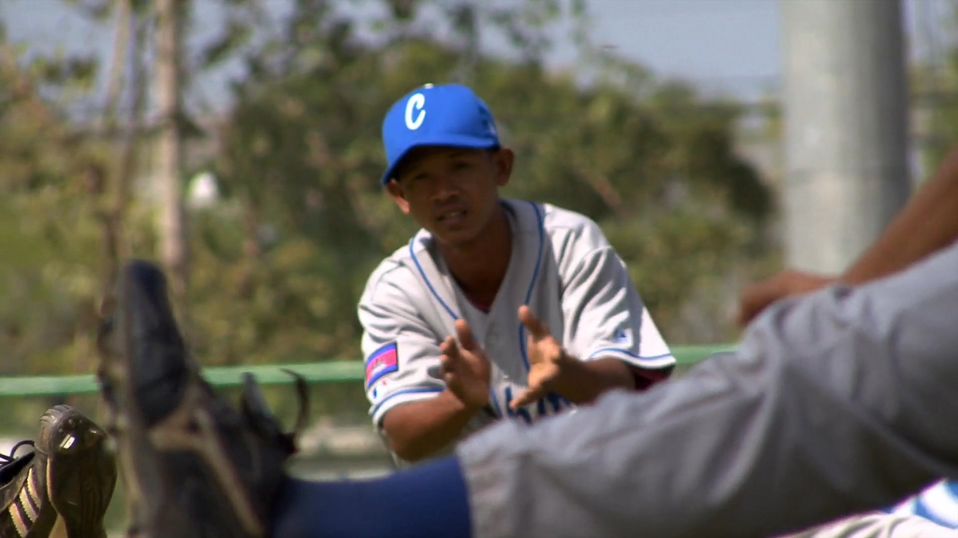 Members of a baseball team participate in drills and warm-up exercises on a professional field. The athletes practice throwing, pitching, and fielding maneuvers during a structured practice session.