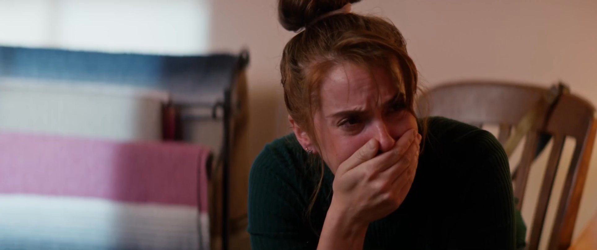 A woman sits in deep distress beside the bed of an unwell man, reflecting on a somber and emotionally charged atmosphere. The scene captures the raw impact of a difficult health crisis on those involved.