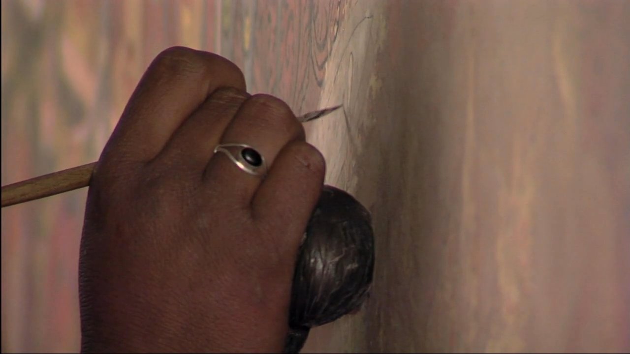 An artisan meticulously restores a detailed Buddhist mural using a fine brush and traditional techniques. The process highlights the vibrant, intricate iconography and the precision required for preservation.