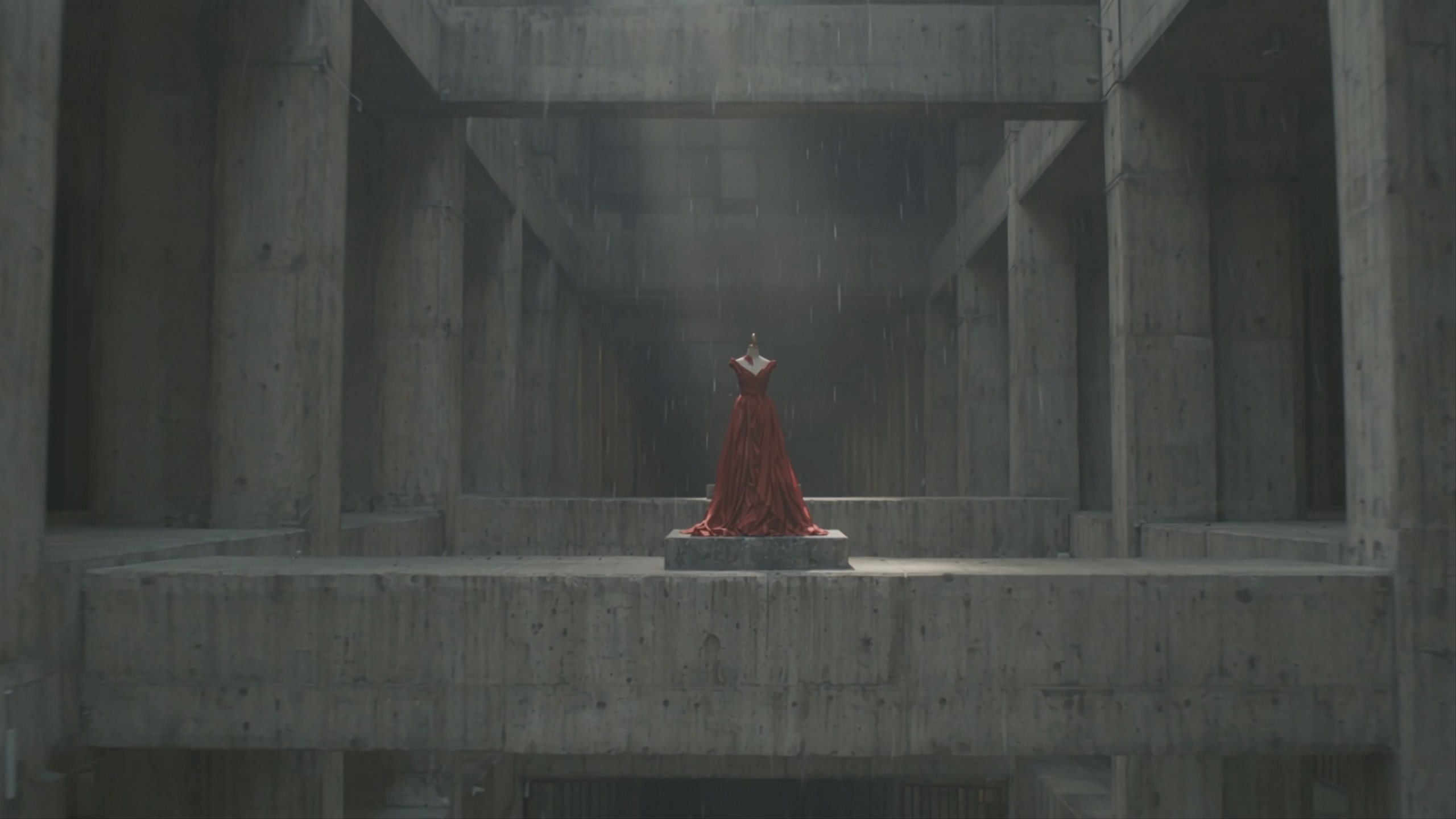 A slow crane move descends through a brutalist museum atrium toward an oxblood gown on a plinth.