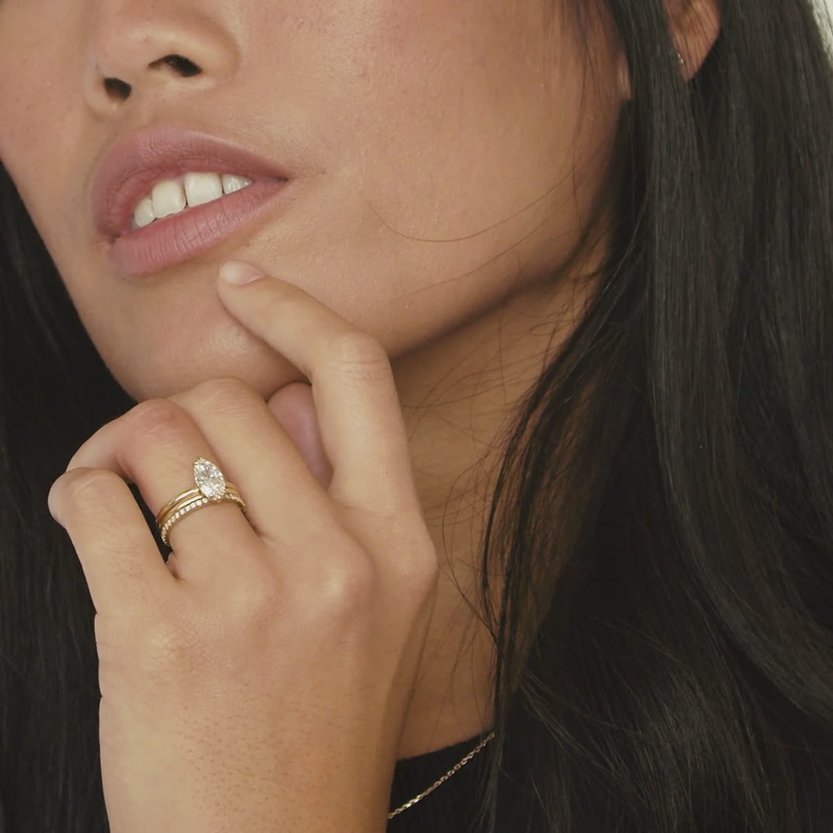 Video of a woman moving her hand across her face while wearing a marquise engagement ring and yellow gold wedding band