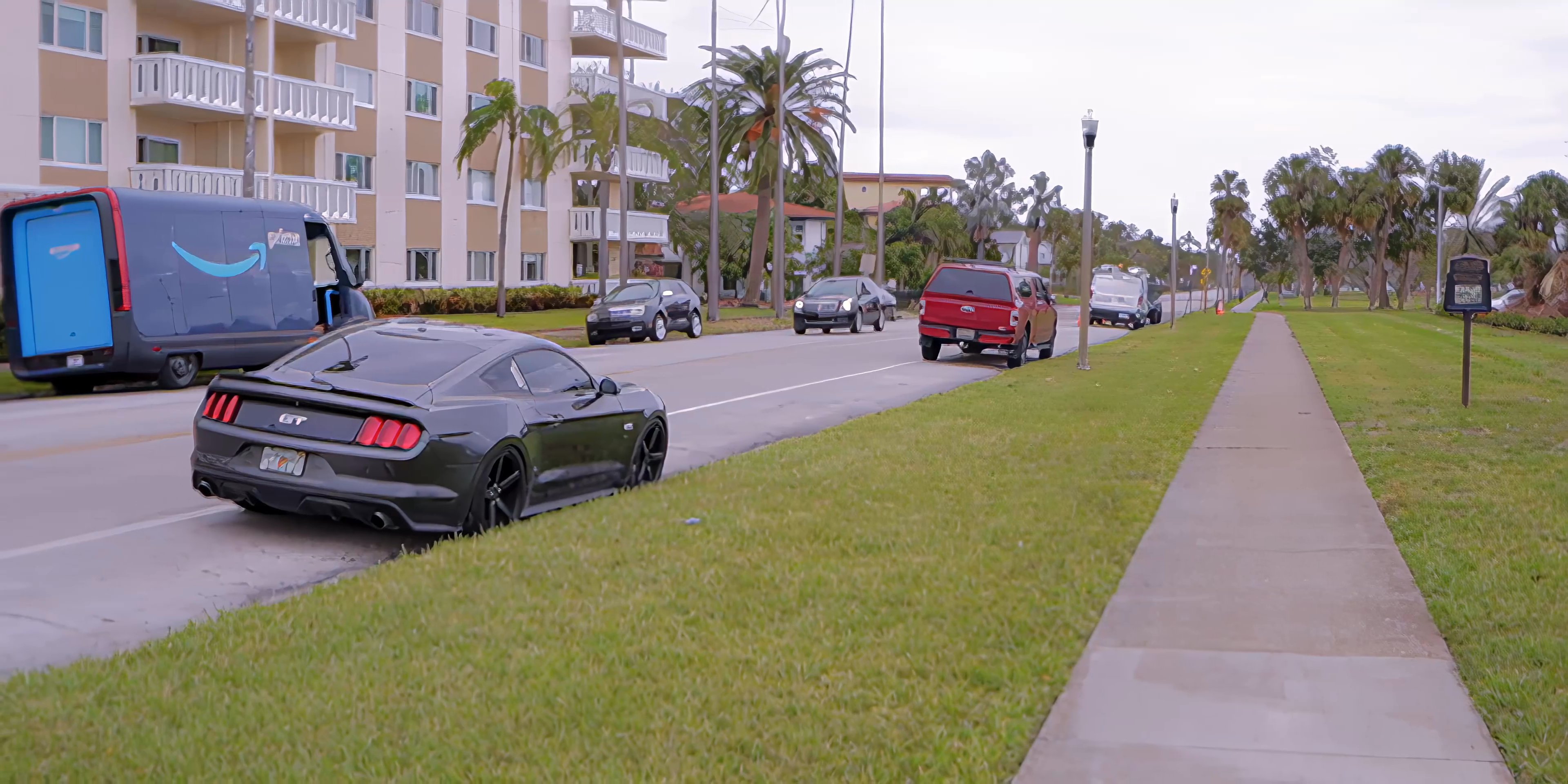 Two men engage in a conversation while sitting on a park bench overlooking a marina. The scene transitions to exterior shots of passing vehicles on a nearby road along a coastal residential area.