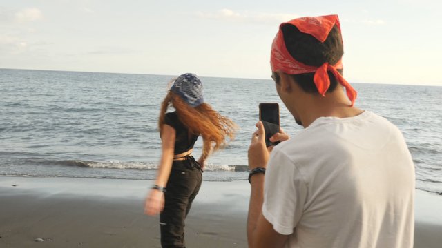 Man films woman on the beach