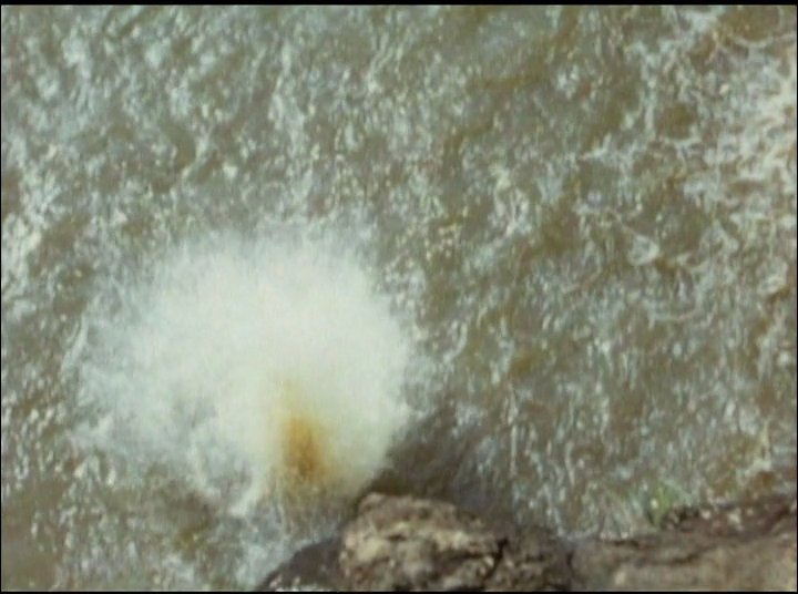 A person leaps from a rocky cliff into turbulent ocean waters, followed by a transition to swimming through heavy surf.