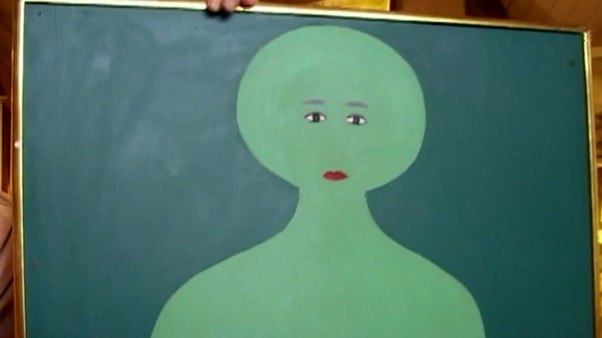 An older man speaks outdoors among lush garden plants while a stylized green figure painting appears in close-up. He recalls buying it in Paris around 1954 and reflects on Renee living a great novel rather than writing one.