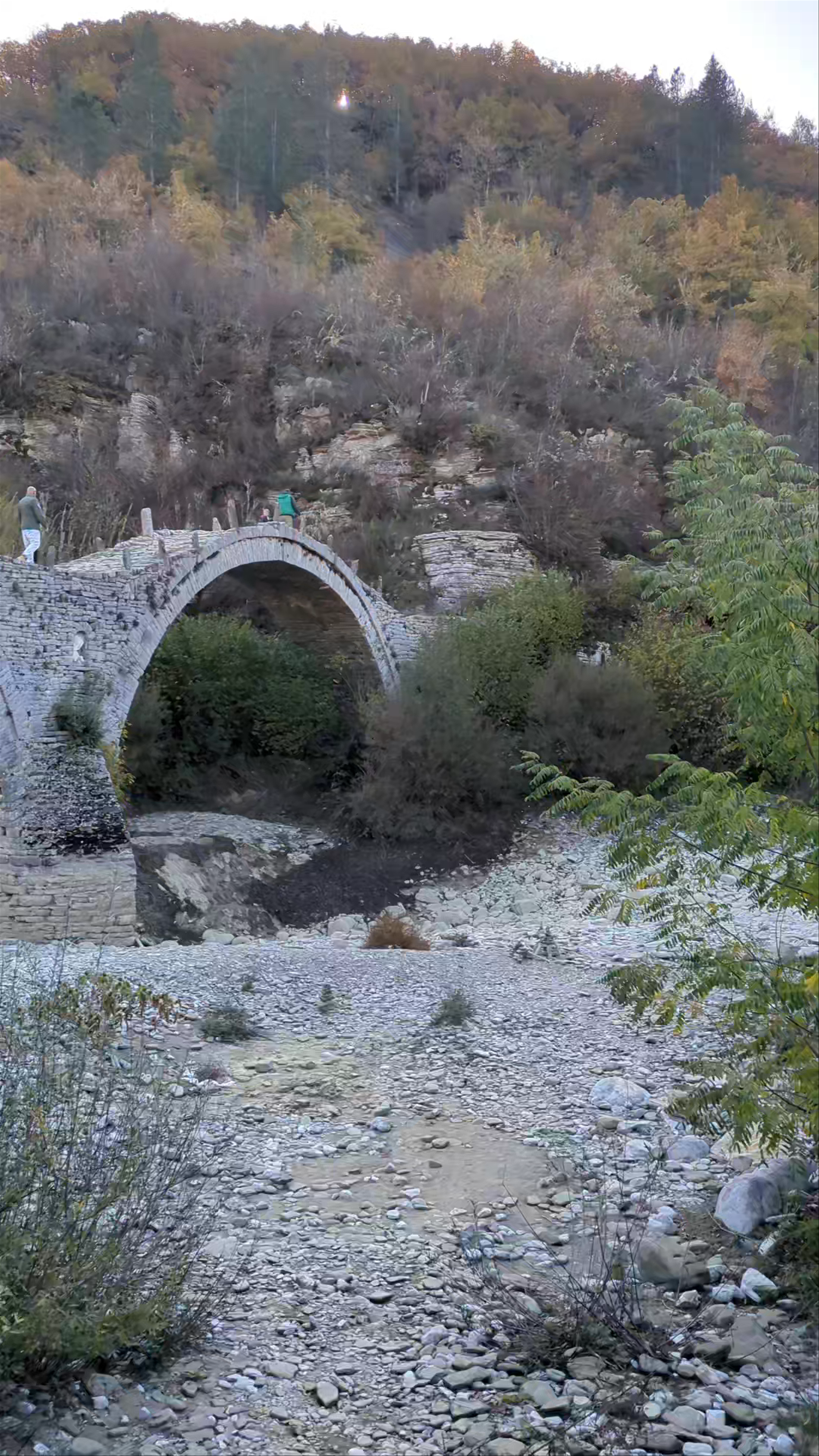 Plakidas Bridge in Kipoi, Greece: Timeless Stone Arch Over Autumn Riverbed