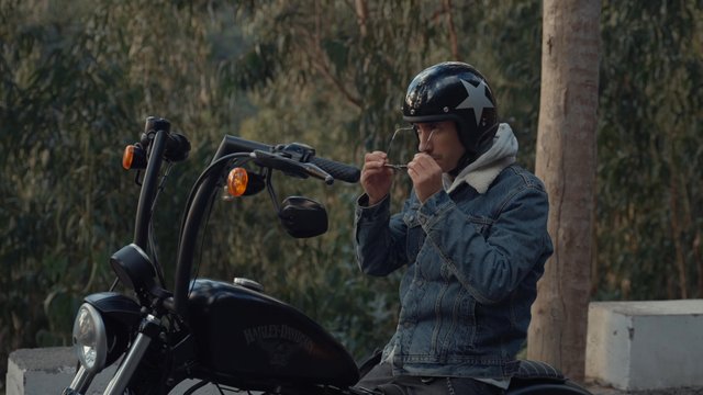 A motorcyclist putting on glasses and accelerating his bike