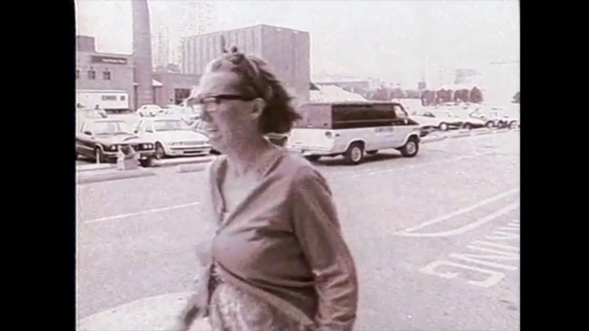 A film crew shoots a scene in an outdoor parking lot before transitioning to two women engaging in a sign language conversation in a park.