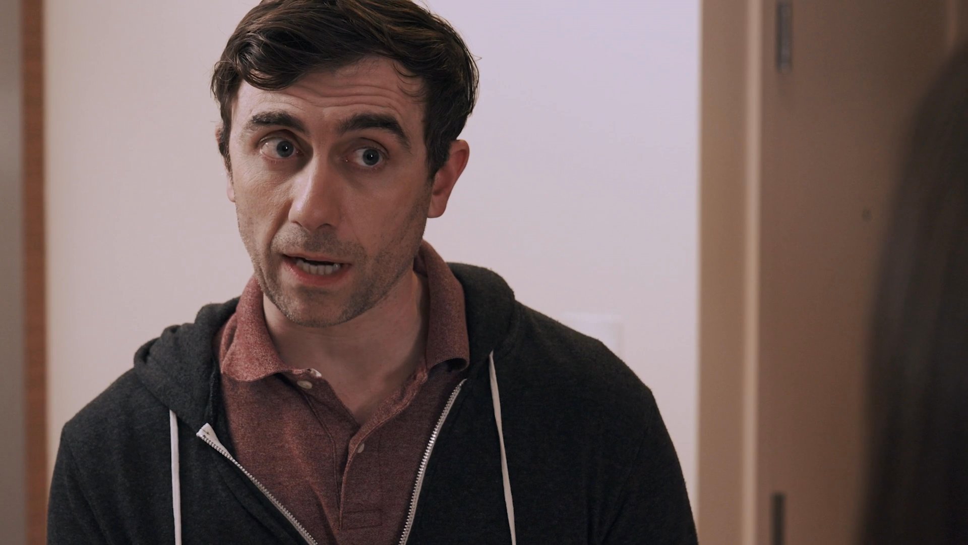 A man and woman engage in a serious, quiet conversation across a kitchen island in a modern home environment.