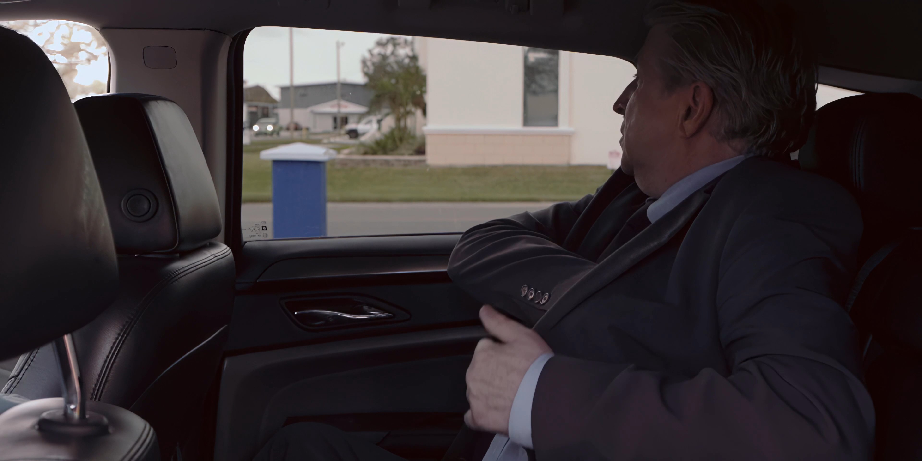 A man in a business suit boards a car and uses a tissue to address congestion before retrieving and using an inhaler to alleviate his respiratory symptoms. He appears to be experiencing a health-related challenge while commuting.