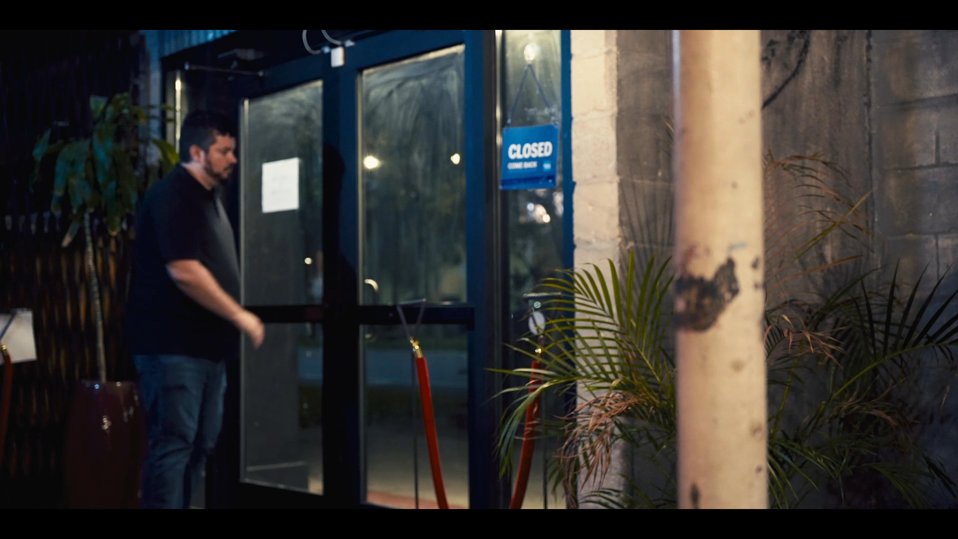 A group travels by car during the day before transitioning to a night scene where a staff member prepares a business for operation by flipping the signage to open.