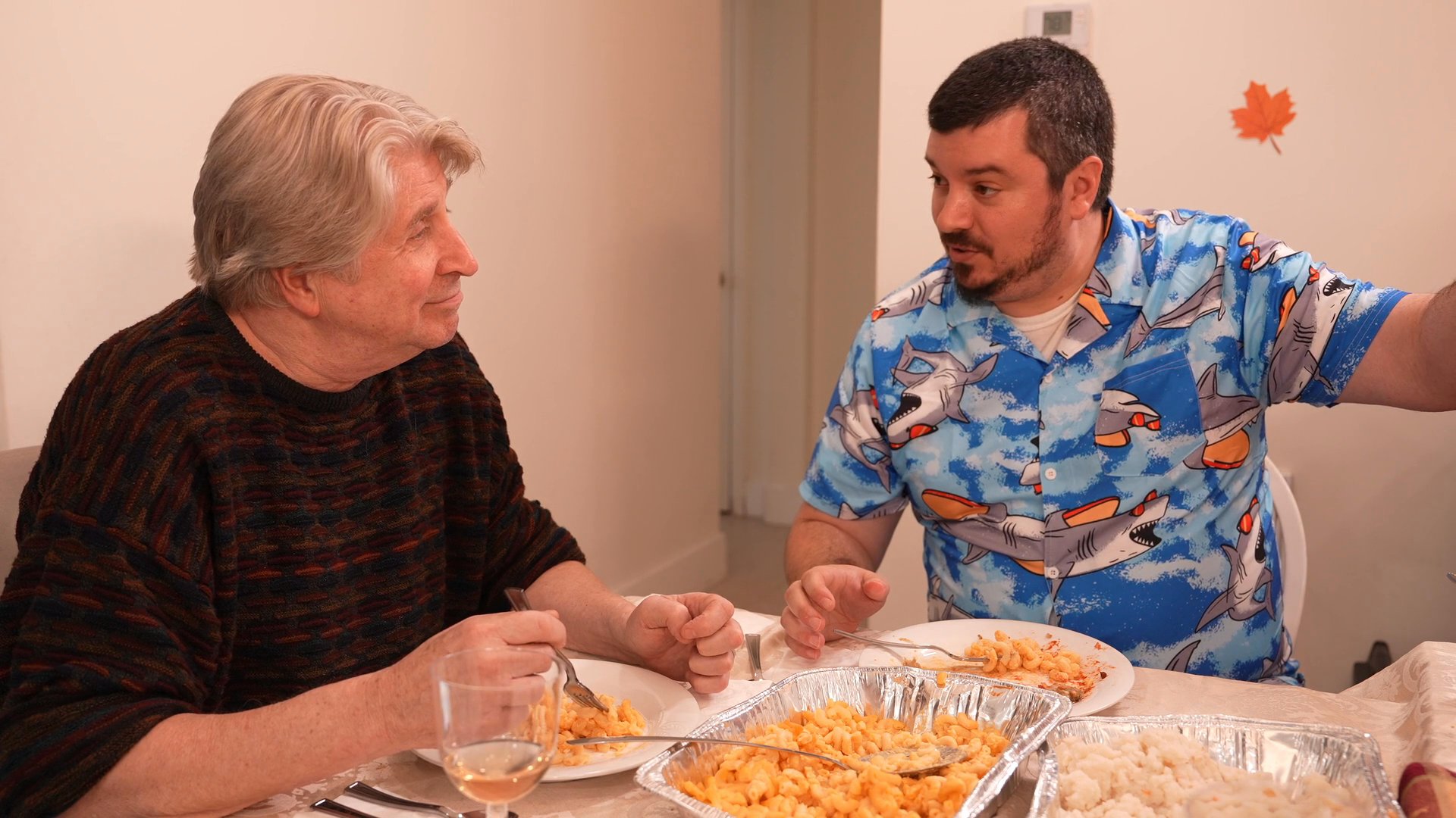 A group of adults and a teenager participate in a casual dinner conversation while sharing a meal at a dining table.