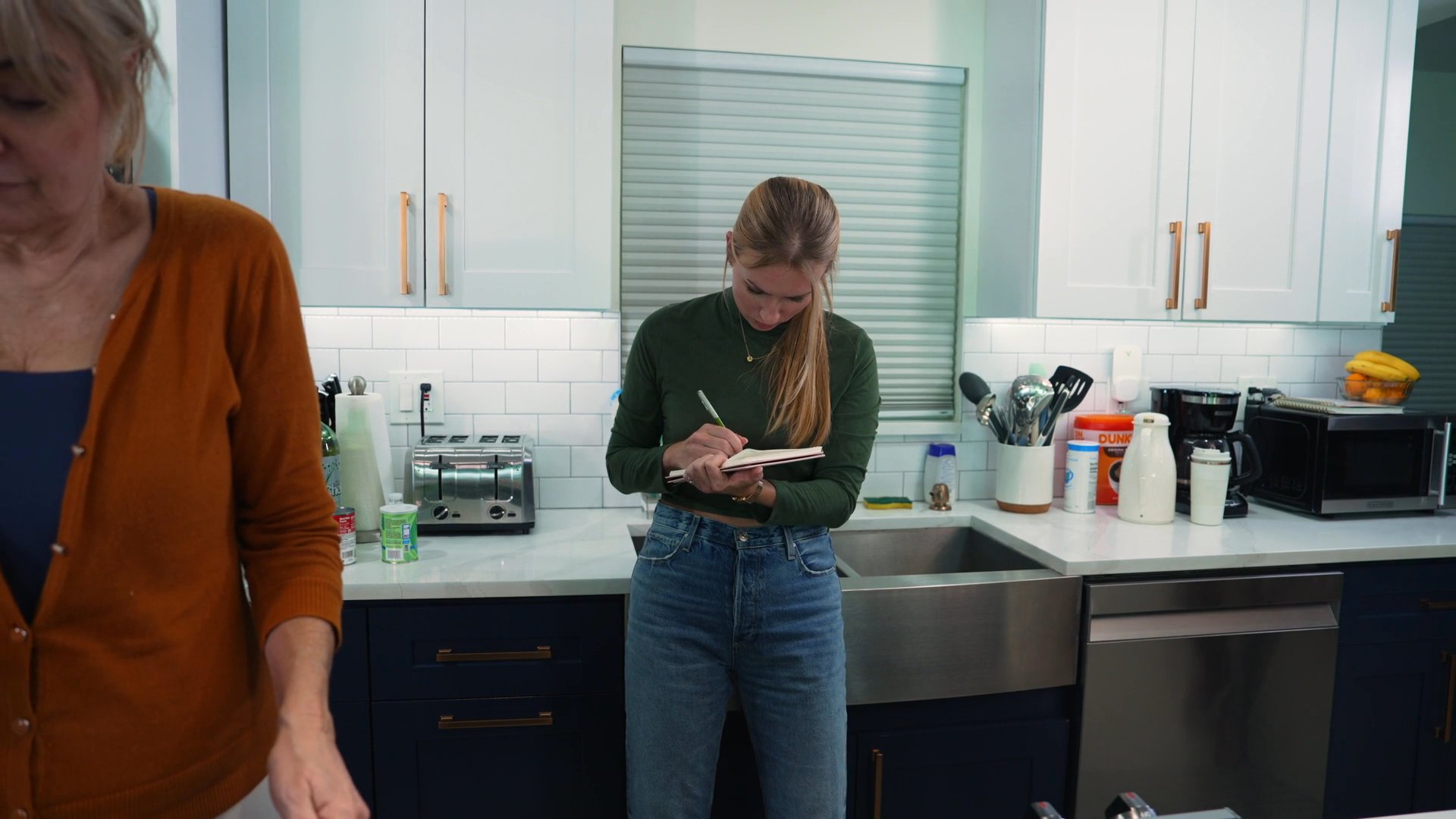 A group of people coordinates tasks and socializes in a home kitchen while preparing for an event. The sequence captures individuals organizing food and communicating in a collaborative residential setting.